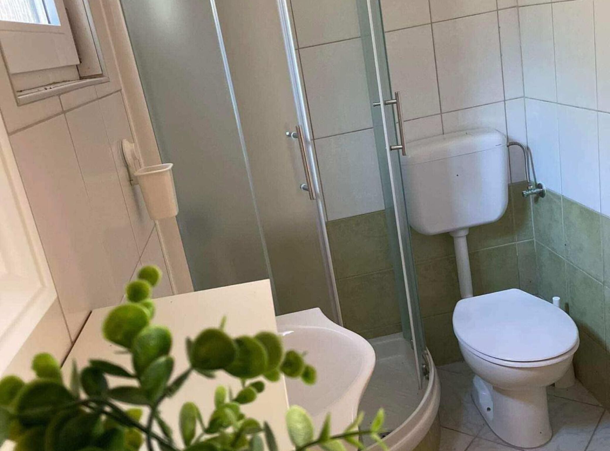 A bathroom with a toilet, a shower enclosure, and a sink.