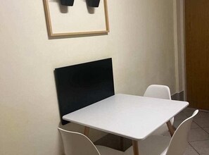 Cozy space with a table and two chairs, a framed picture, and a door.