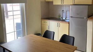 Eine kompakte Küche mit Spüle, Kühlschrank und einer Essecke mit Tisch und Stühlen.