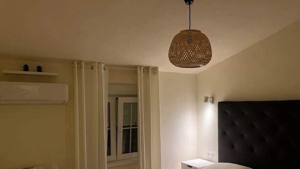 Ein Schlafzimmer mit Bett, Nachttisch, Schreibtisch und einem Fenster mit Vorhängen.