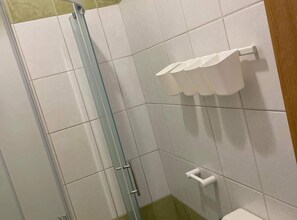 Shower area with a glass door and white tiles.