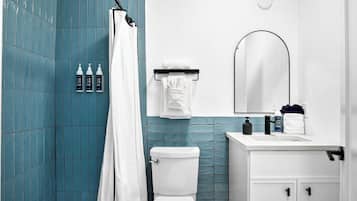 Une salle de bain avec des toilettes blanches, un rideau de douche et un lavabo avec des articles de toilette.