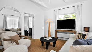 A modern living room with a flat-screen TV, a round coffee table, and a sofa. - SeaSpray Resort (Siesta Key)