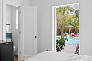 A bedroom with a view of a swimming pool and outdoor seating.