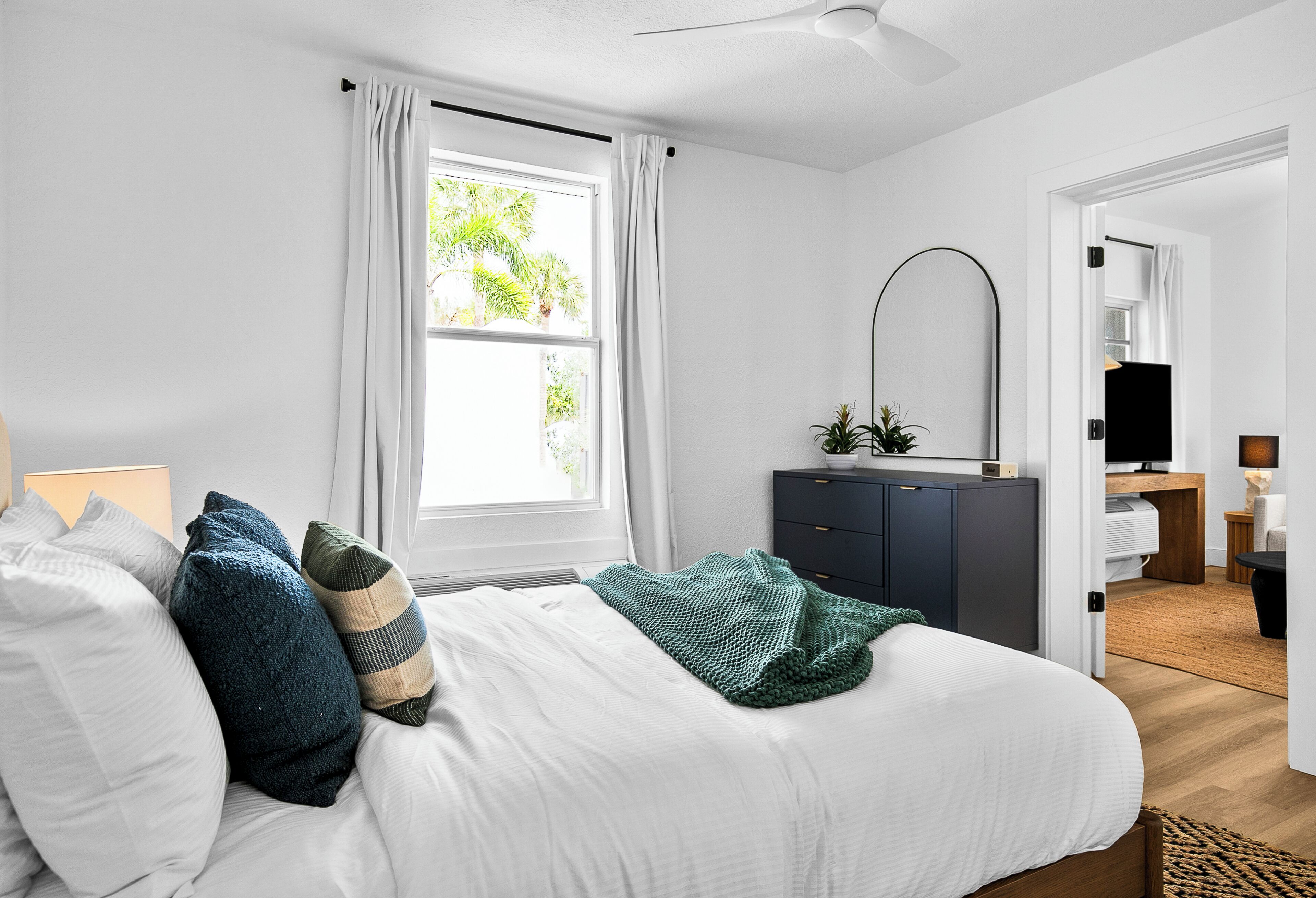 A bedroom with a bed, a desk, a chair, a TV, and a wardrobe.