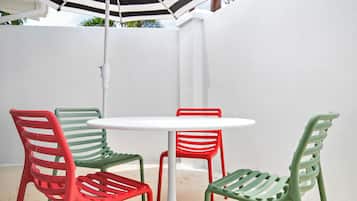 A white table and four chairs with red and green metal frames.