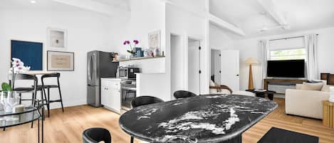 A modern kitchen with a refrigerator, oven, and dining area with chairs and a table.