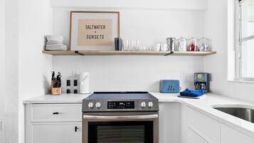 Une cuisine moderne équipée d’un four encastré, d’une machine à café et d’une affiche encadrée au-dessus du plan de travail.