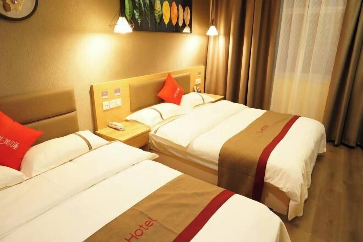A hotel room with two beds, each with a red and white bedspread, a wooden headboard, and a nightstand with a phone.