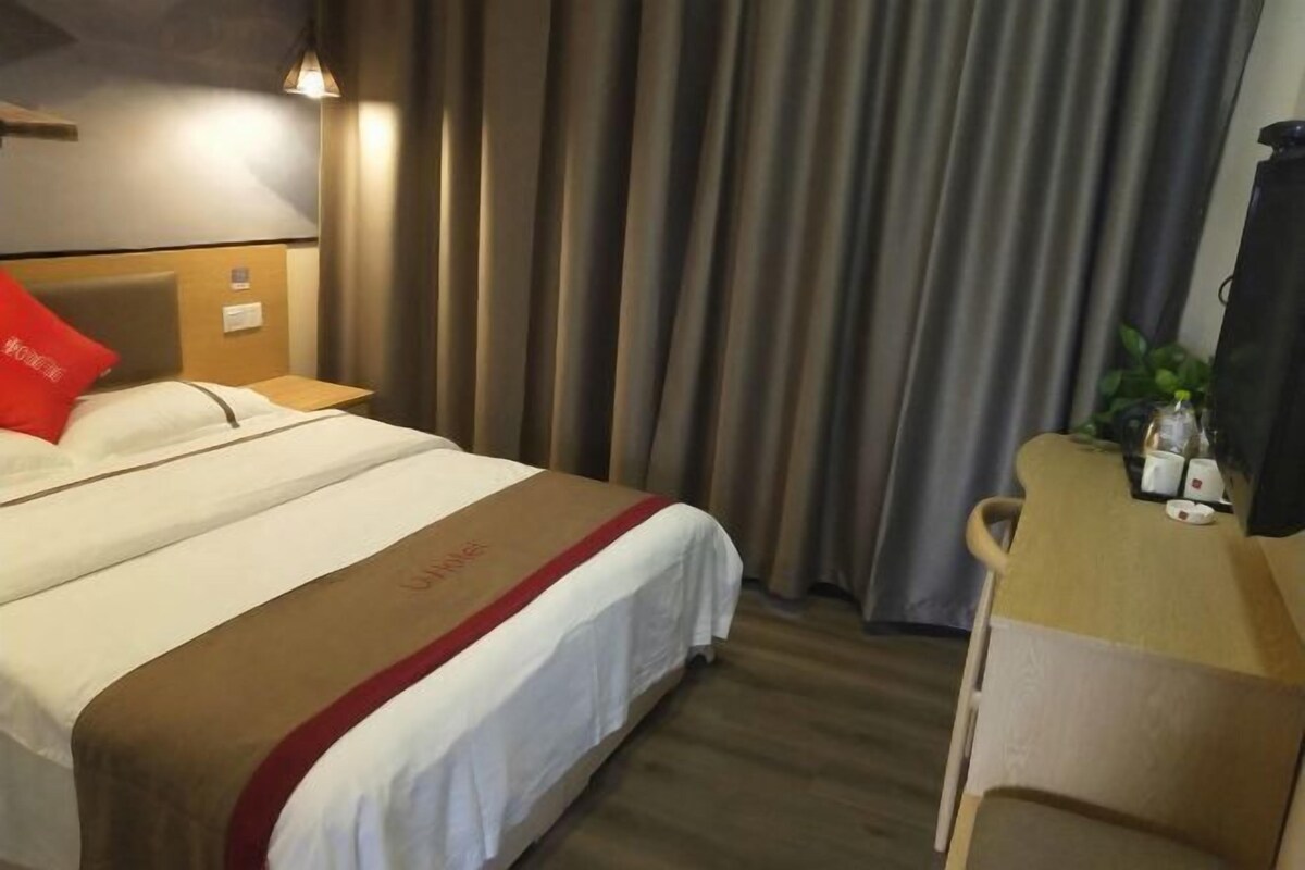 Una habitación de hotel con una cama, un escritorio y cortinas.