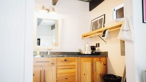 Een compacte keuken met houten kastjes, een aanrecht, een spoelbak en een hangzak.
