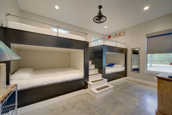 A bunk bed room with a staircase, a mirror, and a 'BEER' sign.