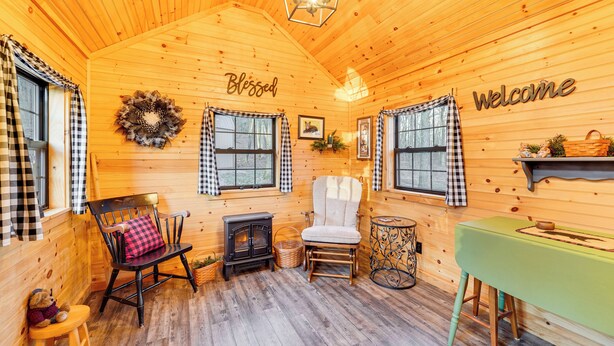 L’intérieur chaleureux d’un chalet avec une cheminée, un fauteuil à bascule, une table et un banc.