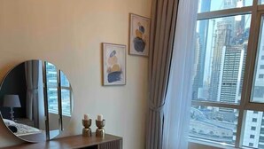 Habitación de hotel con una cama grande, un espejo redondo, un aparador de madera y vistas de la ciudad a través de la ventana.