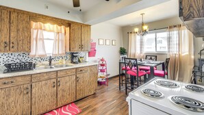 A kitchen with wooden cabinets, a white stove, and a dining area with red chairs. - 8 Mi to Dtwn Cleveland: Quiet Home w/ Fenced Yard (Garfield Heights)