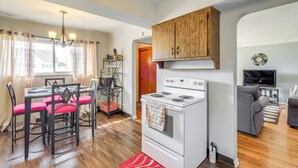 A compact kitchen with a stove, dining table with chairs, and a living area with a sofa and TV. - 8 Mi to Dtwn Cleveland: Quiet Home w/ Fenced Yard (Garfield Heights)
