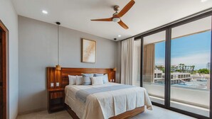 A modern hotel room with a large bed, wooden headboard, and a ceiling fan. - Arch View Master Bedroom Condo Cabo San Lucas • Rooftop Infinity Pool | 101 (Cabo San Lucas)