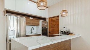 A modern kitchen with a large island, built-in appliances, and wooden accents. - Arch View Condo Cabo San Lucas • 2nd Floor | Rooftop Pool | 203 (Cabo San Lucas)