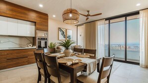 A modern dining area with a wooden table, chairs, and a ceiling fan. - Arch View Condo Cabo San Lucas • Living Room & Master | Suite 104 (Cabo San Lucas)