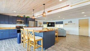 Una cocina moderna con armarios azules, sillas de madera y una isla central.