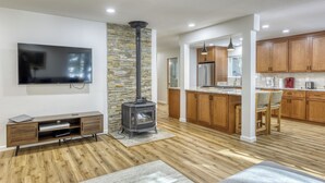 A modern living room with a stone wall, a flat-screen TV, a wooden entertainment unit, and a fireplace. - Tahoe Donner 4BR Escape | Hot Tub & Year-Round Fun (Truckee)