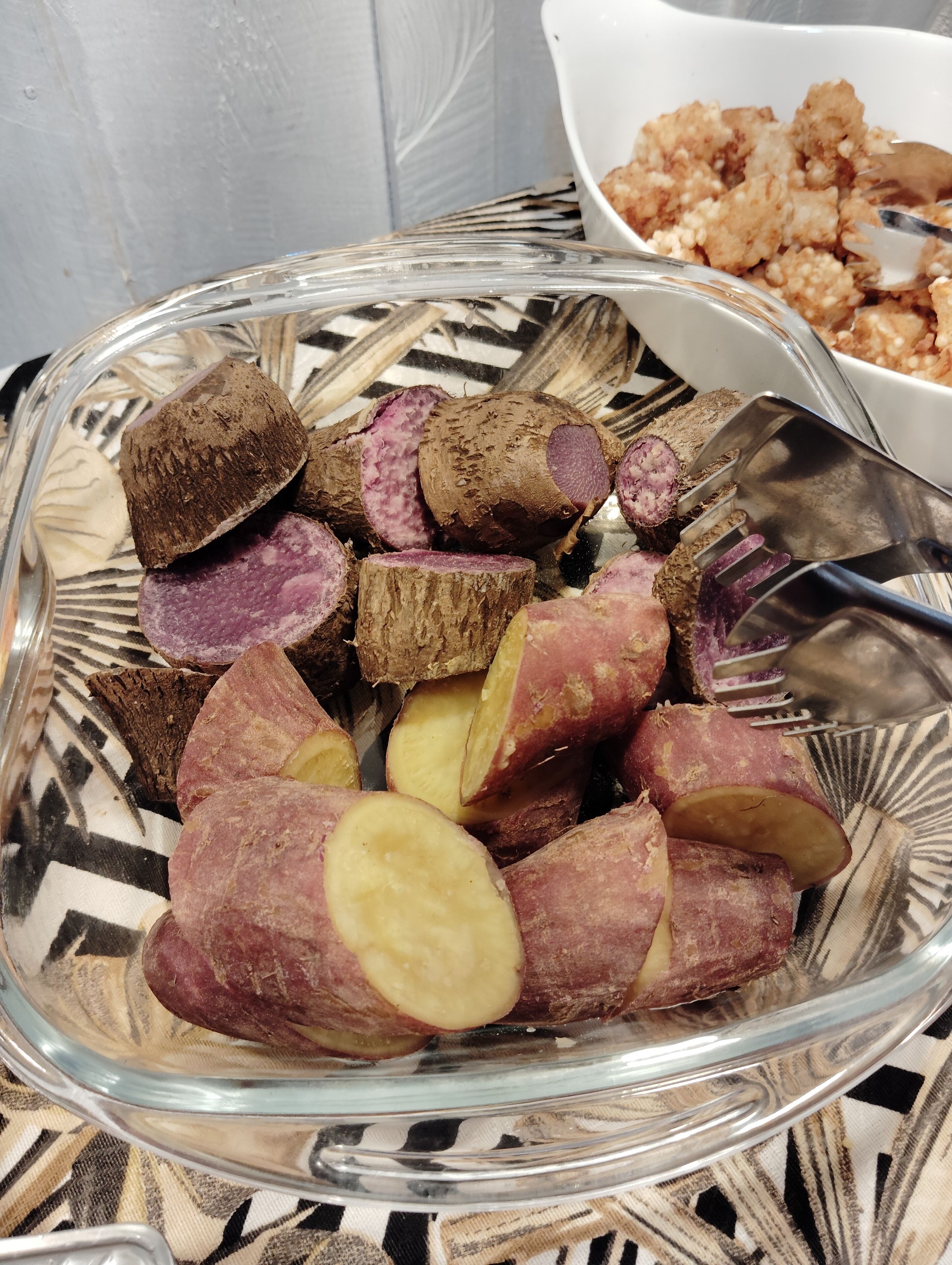 A glass bowl filled with sliced sweet potatoes and a fork.