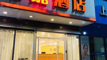 A hotel entrance with a glass door, a reception desk inside, and a sign with Chinese characters.