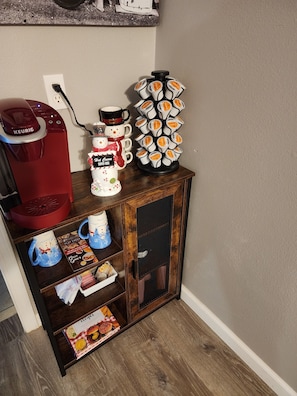 Una cocina equipada con cafetera, un escurridor para tazas y un soporte para cápsulas de café.