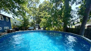 Ein klarer, blauer Swimmingpool, umgeben von Bäumen und einer Holzterrasse.