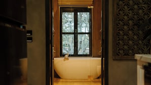Un baño con bañera, ventana y pared decorada.