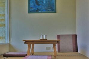 A room with a wooden table, a mat, and a painting on the wall. - Qingjing Tixiang Panoramic Hostel (Nantou)