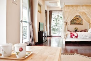A room with a bed, a TV, a table with cups, and a balcony view. - Qingjing Tixiang Panoramic Hostel (Nantou)