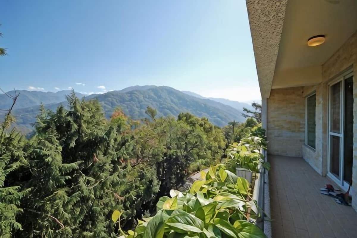 A balcony with a view of mountains, a stone building, and a door.