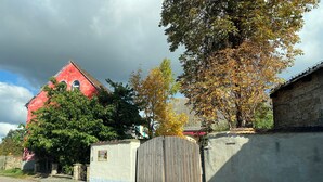 Un bâtiment rouge avec un chemin pavé de pierres et une porte en bois.