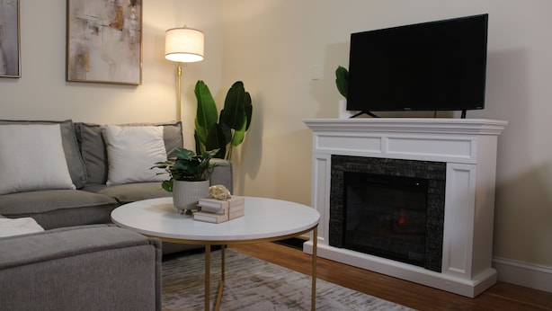 A living room with a sofa, a round coffee table, a fireplace, a television, and a lamp.