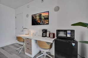 A modern kitchen with a white countertop, two wooden chairs, a microwave, a toaster, and a coffee maker.
