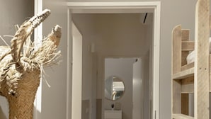 A hallway with a white door, a round mirror, and a wooden shelf unit. - Holiday Home in Yn e Lijte With Water Sports (Grou)