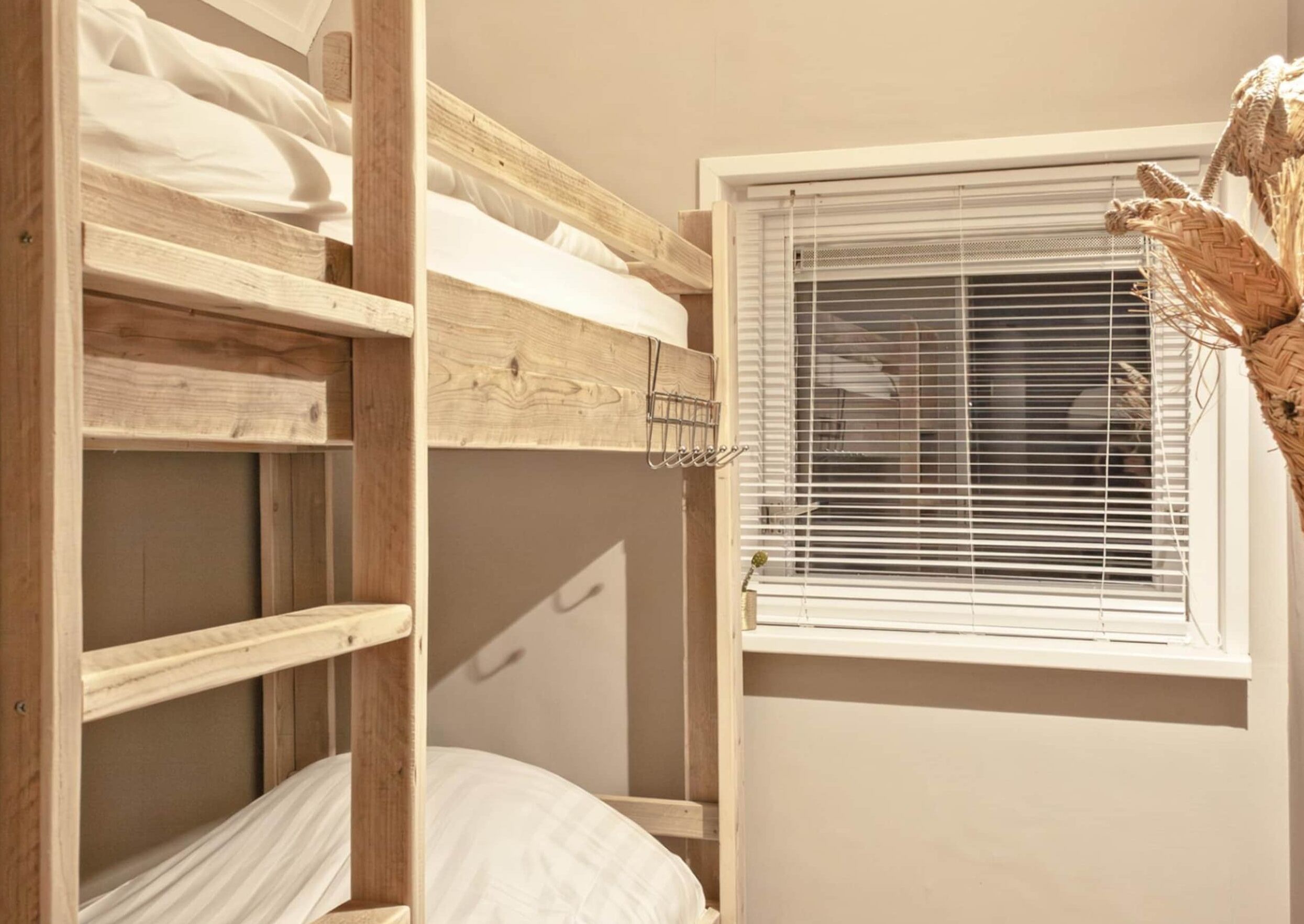 Un lit superposé avec une fenêtre et un panier en osier.