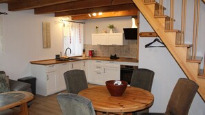 Une cuisine chaleureuse avec des meubles en bois, une table à manger avec des chaises et un escalier.