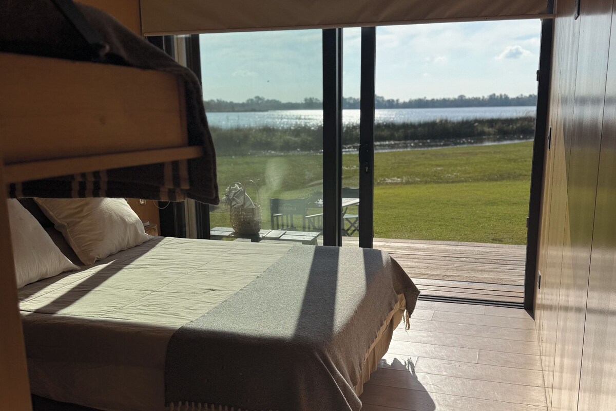 A bedroom with a large bed, a view of a lake, and a balcony.