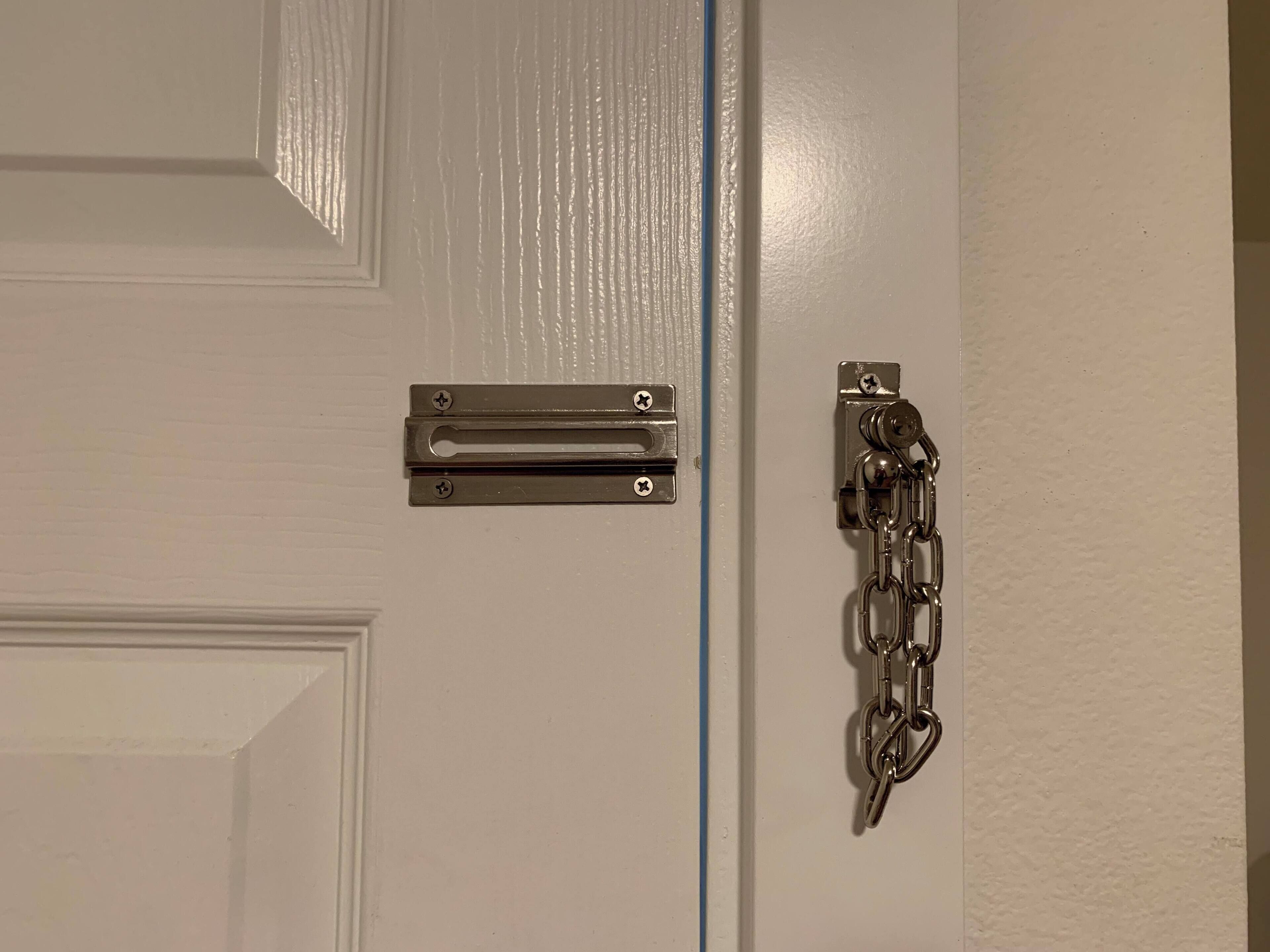A white door with a metal handle and a chain lock.