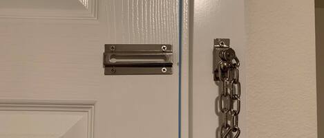 A white door with a metal handle and a chain lock.