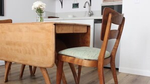 Ein Holztisch mit integriertem Sitzbank, ein gepolsterter Stuhl und eine Vase mit Blumen.