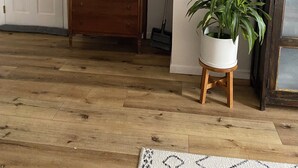 Ein Zimmer mit einem hölzernen Schminktisch, einem Spiegel, einem Blumentopf, einem Gemälde und einem Fernseher.