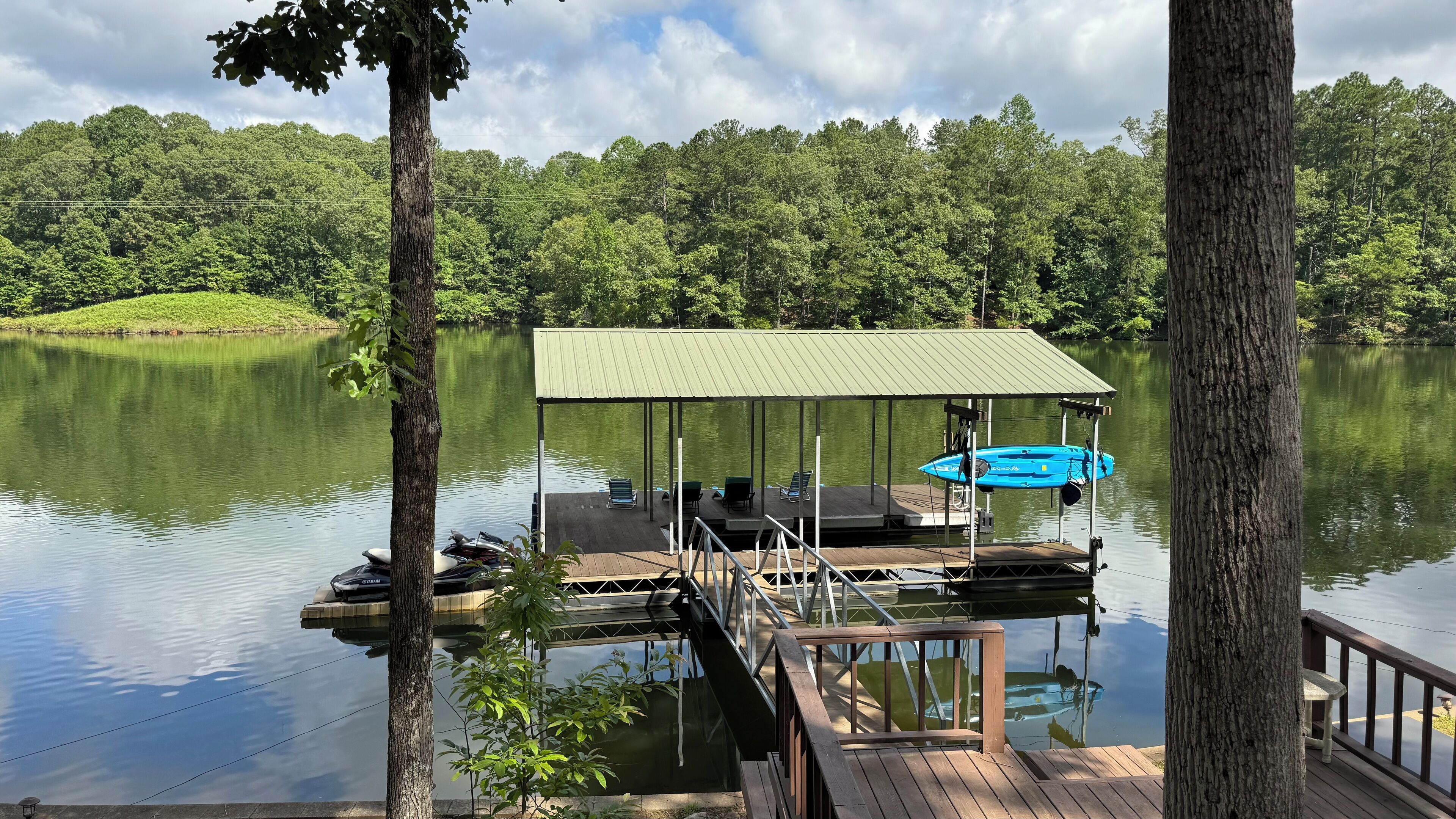 A dock with a covered seating area, a kayak, and a paddleboard.