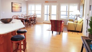 A spacious living area with a dining table, chairs, a sofa, and a coffee table. There is a ceiling fan, a floor lamp, and a painting on the wall. - Serene Waterfront Lake Wedowee Home (Wedowee)
