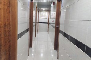 A corridor with a tiled floor, wooden doors, and a patterned wall at the end. - Wing Tai Guest House (Hong Kong)