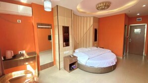 A hotel room with a round bed, a small bedside table, a mirror, and a wall-mounted air conditioning unit. - Shanghai Longting Hotel (Shanghai)