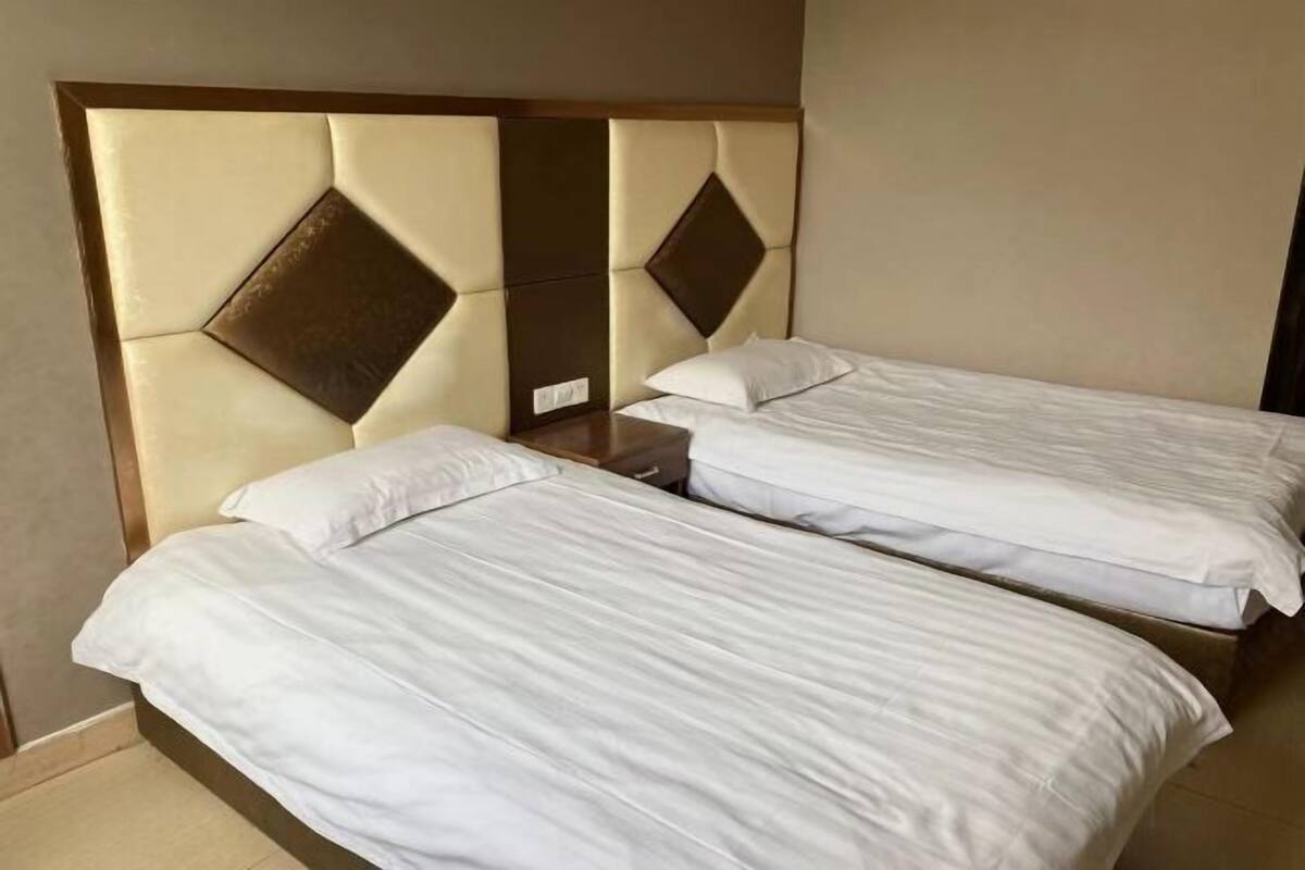 A hotel room with two single beds, a wooden headboard, and a mirror.