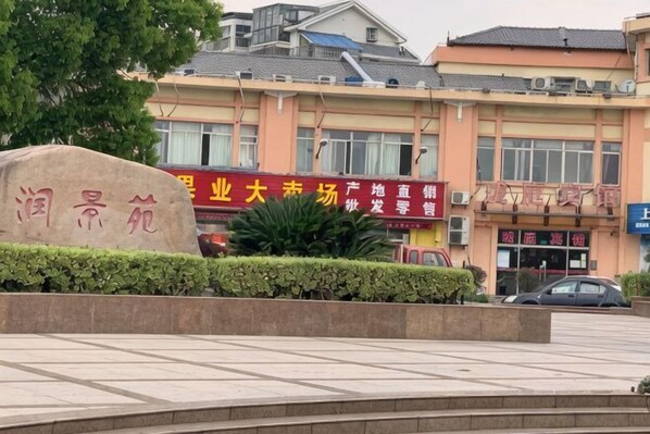 A building with signage in a foreign language, a stone monument, and a car parked in front. - Shanghai Longting Hotel (Shanghai)